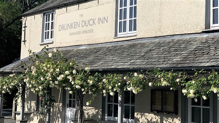 The facade of the dog-friendly Drunk Duck Inn in Barngates in the Lake District with roses clinging to its front